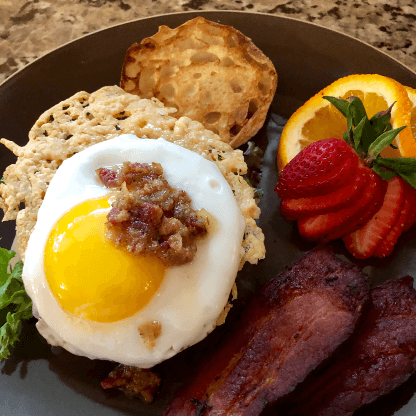 Round brown plate with egg, bacon, bread, a fruit