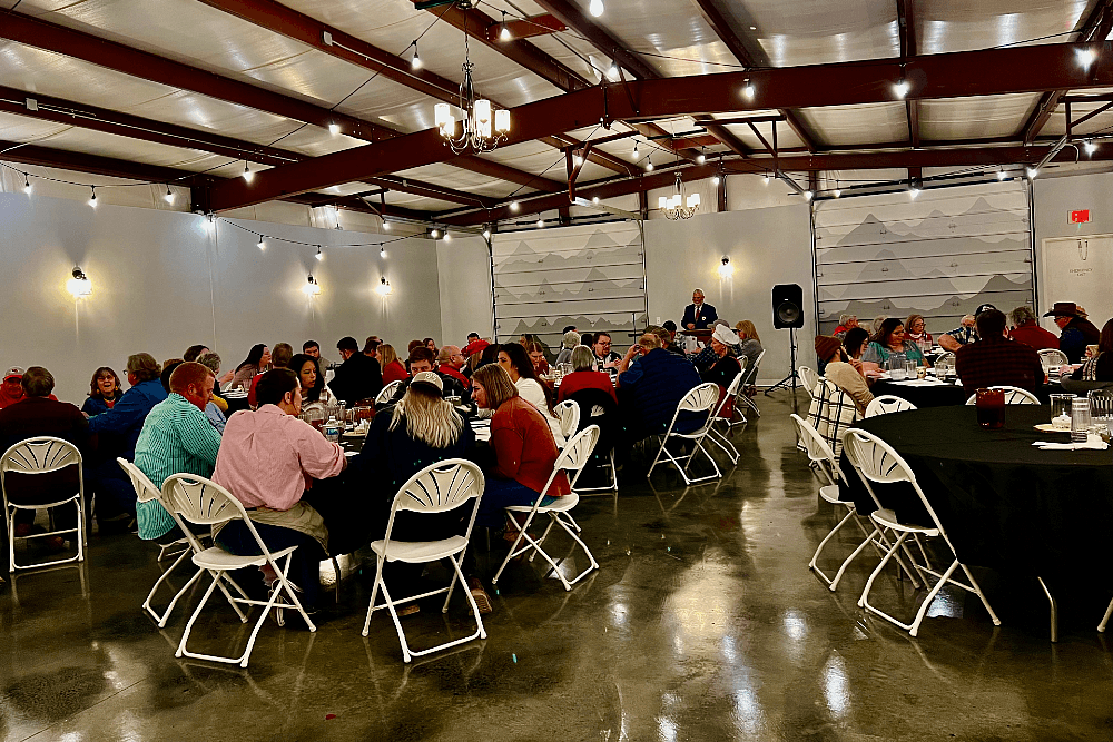 A large hall with several tables full of people gathered for a private event