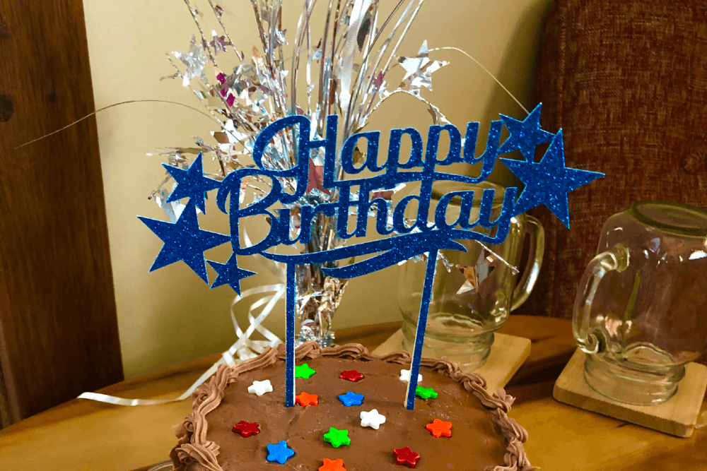 Chocolate cake with star sprinkles and a sparkly blue happy birthday sign