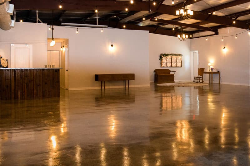 A spacious interior with polished concrete flooring, pendant lights, and minimal furniture.