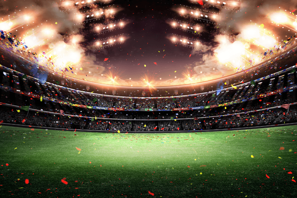 An expansive open air stadium with lights on at night, smoke cannons and confetti in the air