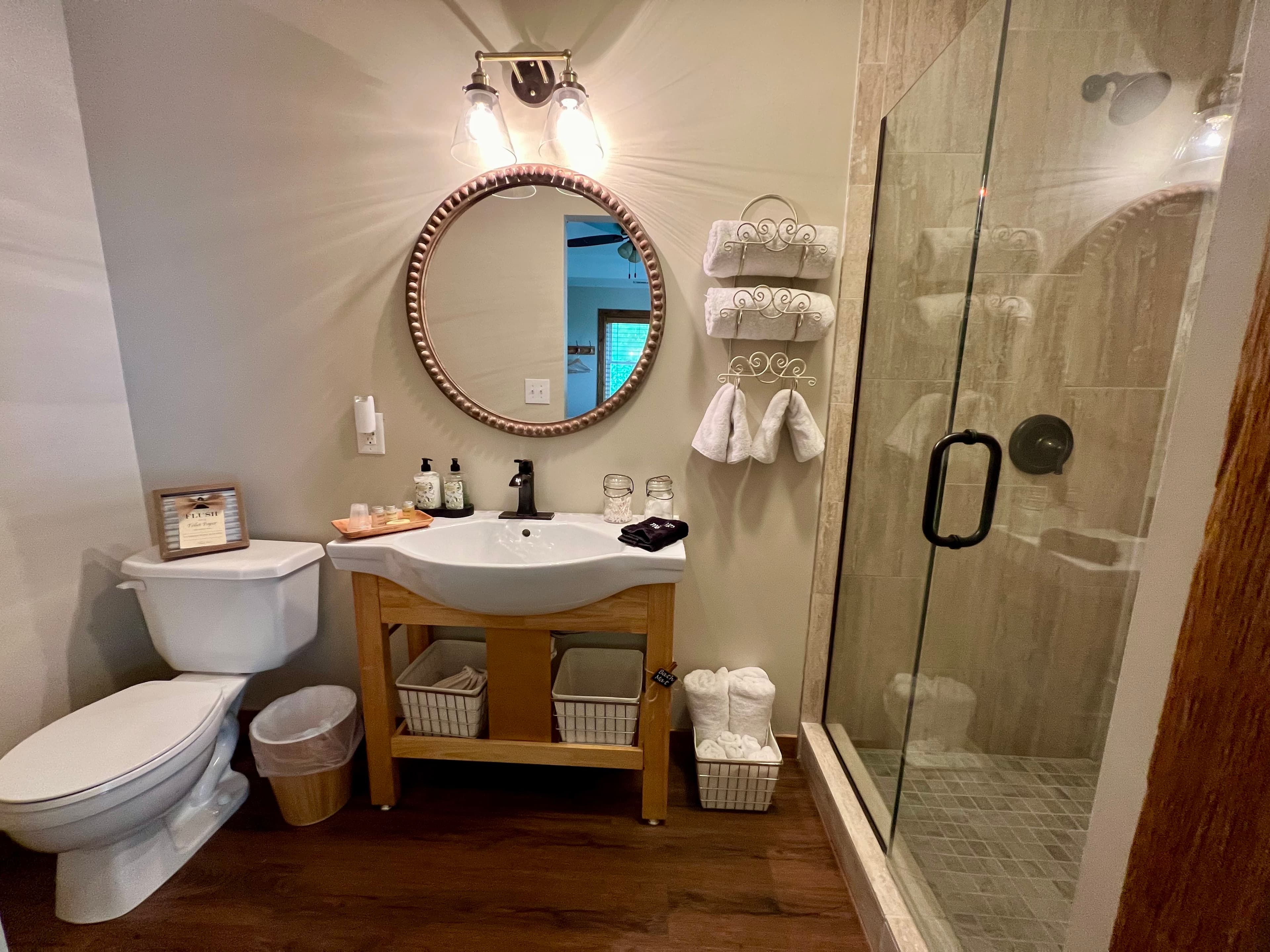 Modern bathroom featuring a mirror, sink with wooden stand, shower enclosure, and neatly arranged towels.