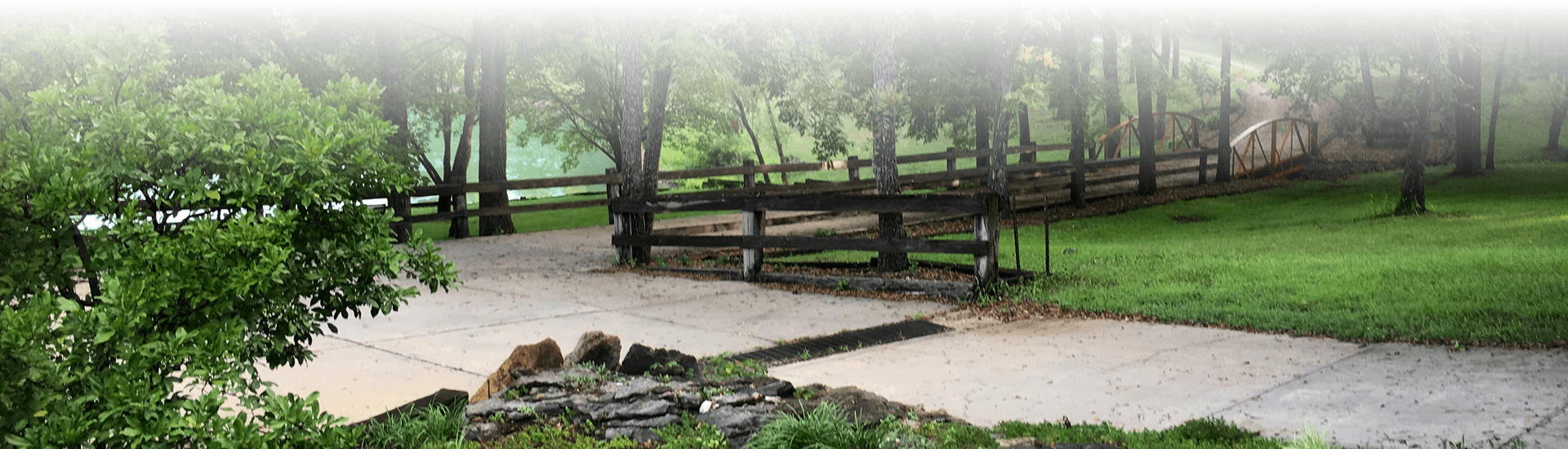 Heavily treed walkway with bridge and pond