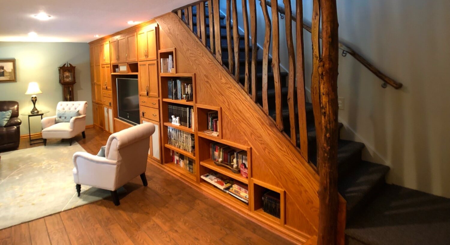 Staircase with shelving, two white chairs and tv