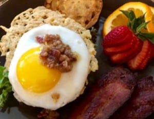open faced fried egg sandwich with bacon jam, crispy bacon and sliced strawberries
