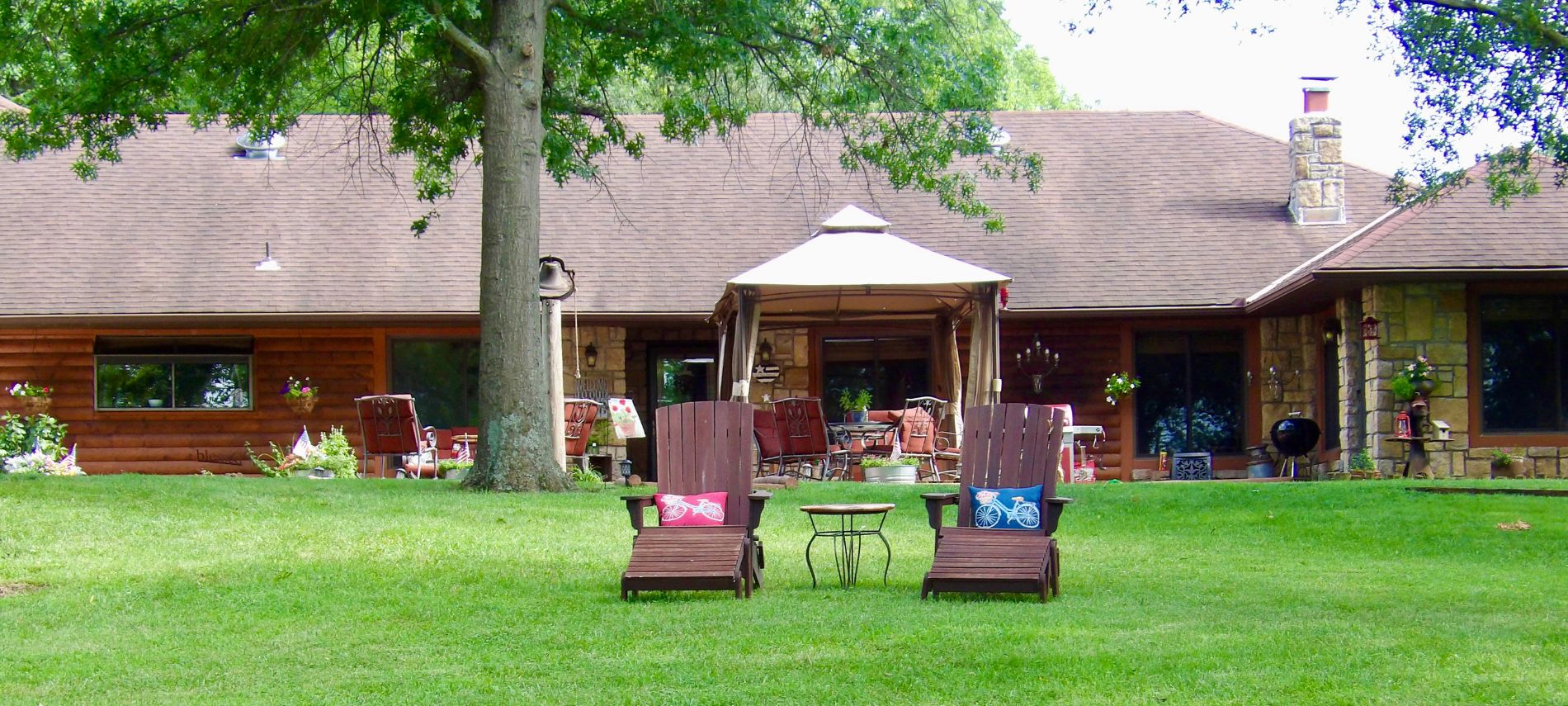 Two wooden lounge chairs on the grassy lawn overlooking two gazebos and large pond