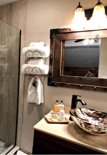 Walnut guest bath, walk-in shower with glass door, vanity with vessel sink and rectangular mirror
